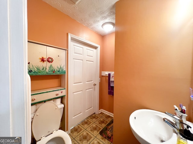 bathroom with toilet, sink, and a textured ceiling