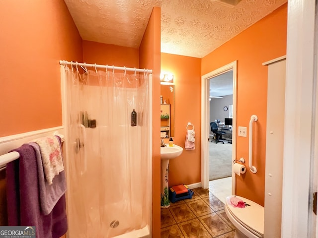 bathroom featuring toilet, tile patterned floors, a textured ceiling, and a shower with shower curtain