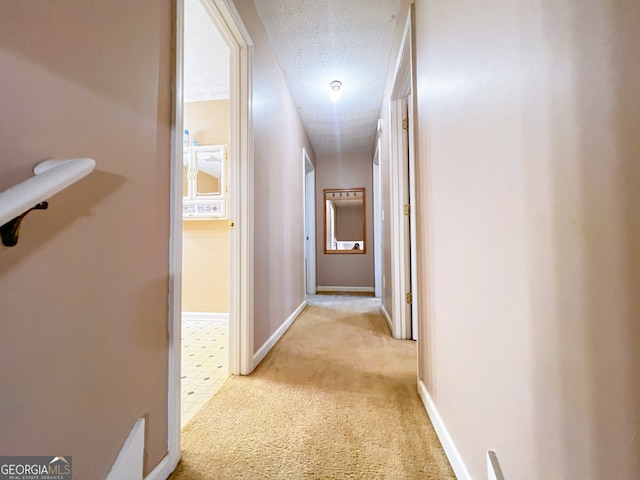 hall featuring a textured ceiling and light colored carpet