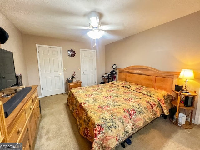 carpeted bedroom featuring ceiling fan and a textured ceiling