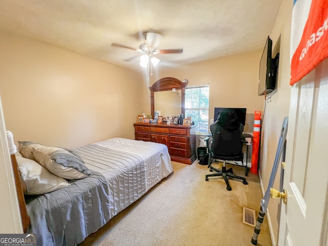 carpeted bedroom featuring a textured ceiling and ceiling fan