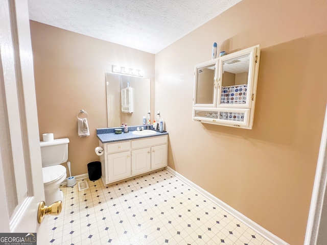 bathroom featuring vanity, toilet, and a textured ceiling