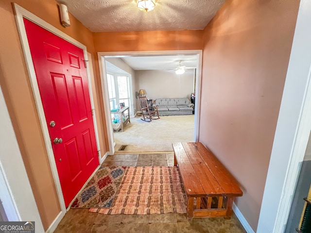 entrance foyer featuring carpet, a textured ceiling, and ceiling fan