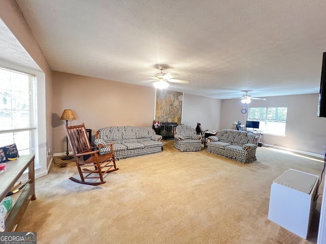 carpeted living room with a stone fireplace, a textured ceiling, and ceiling fan