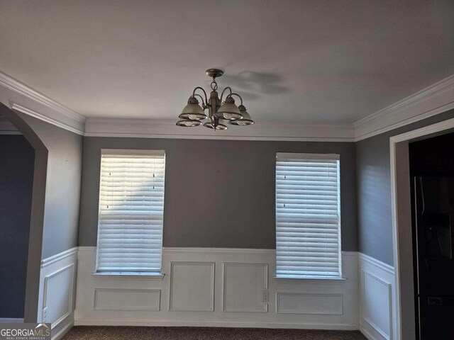 unfurnished dining area with crown molding, carpet, and an inviting chandelier