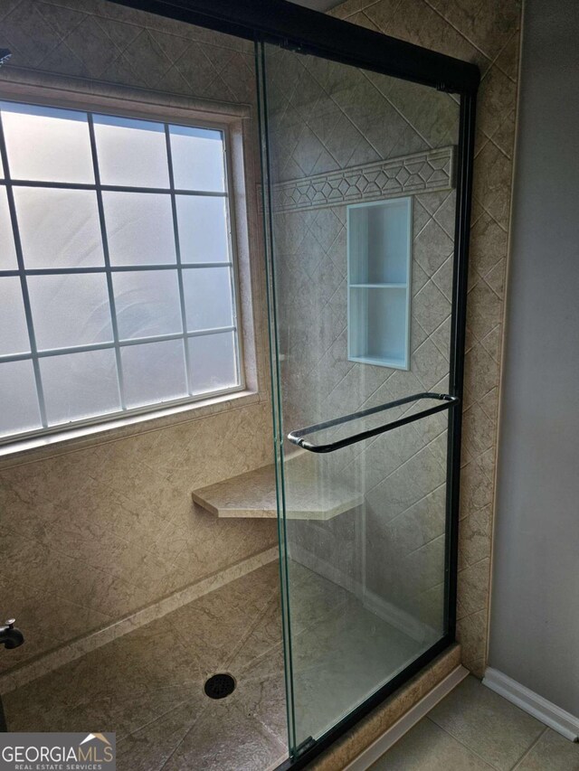 bathroom with tile patterned floors, a healthy amount of sunlight, and a shower with shower door