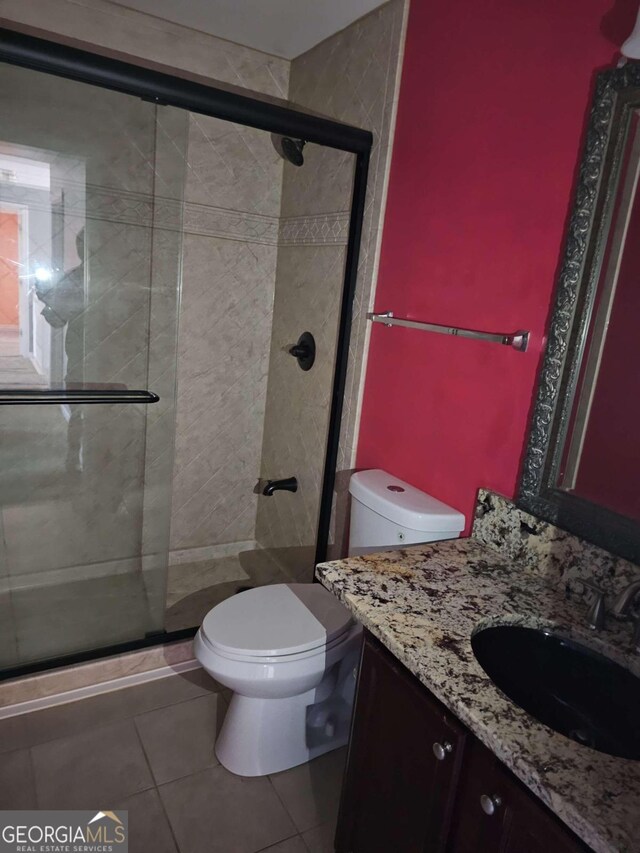 bathroom featuring tile patterned floors, vanity, toilet, and a shower with door