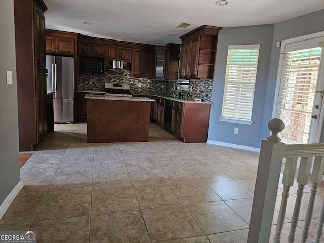 kitchen with range hood, tasteful backsplash, a kitchen island, dark brown cabinetry, and stainless steel appliances