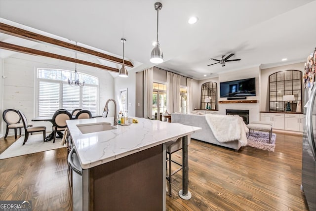 kitchen with hanging light fixtures, a wealth of natural light, sink, and a kitchen island with sink