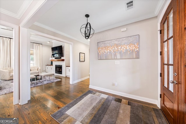 entryway featuring dark hardwood / wood-style flooring, a notable chandelier, and ornamental molding