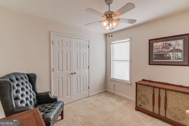 living area with light carpet and ceiling fan