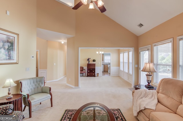 living room featuring ceiling fan with notable chandelier, light colored carpet, and high vaulted ceiling