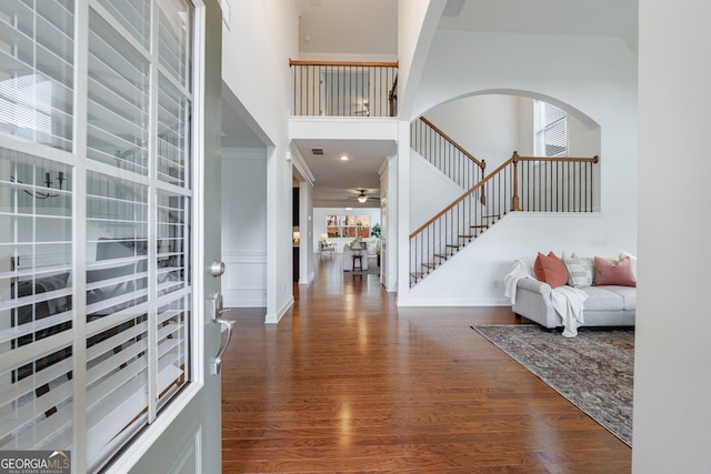 entrance foyer with ceiling fan, wood-type flooring, and a high ceiling