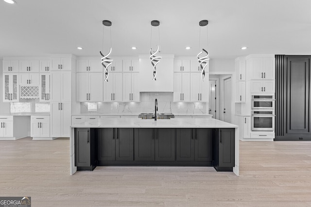 kitchen with decorative backsplash, white cabinetry, stainless steel double oven, and decorative light fixtures