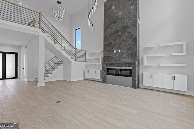 unfurnished living room with a fireplace, light hardwood / wood-style flooring, and a towering ceiling