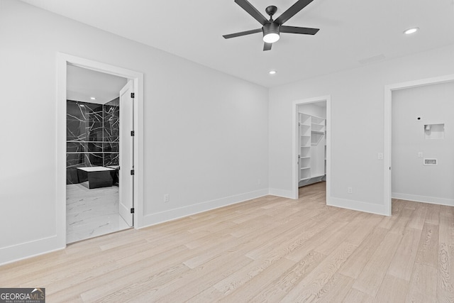 unfurnished bedroom with a spacious closet, ceiling fan, light hardwood / wood-style flooring, ensuite bathroom, and a closet