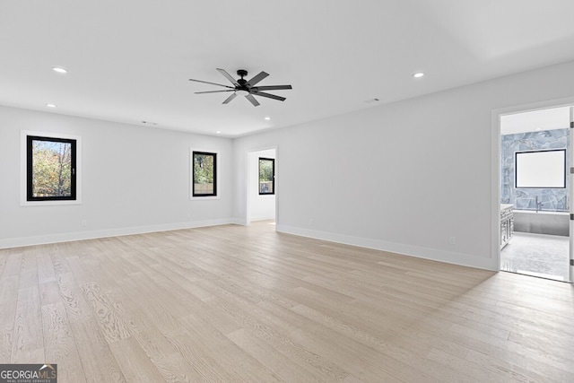 spare room featuring ceiling fan, a healthy amount of sunlight, and light hardwood / wood-style floors