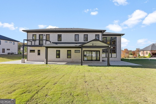 rear view of house with a patio, a balcony, and a lawn