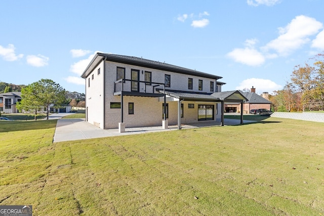 rear view of property featuring a balcony, a yard, and a patio