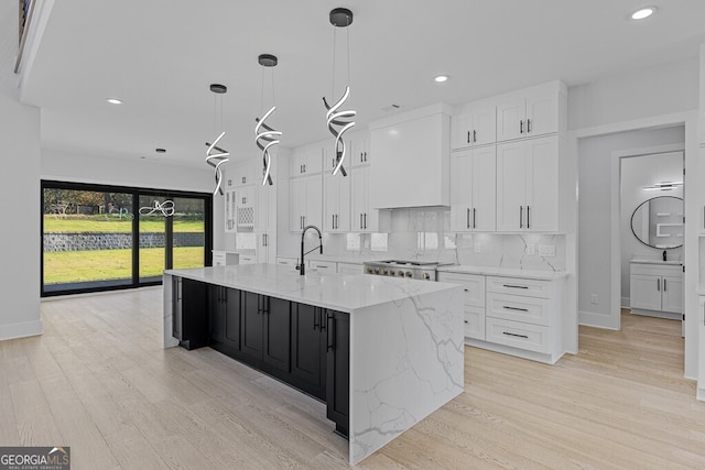 kitchen with white cabinets, pendant lighting, light hardwood / wood-style floors, and a large island