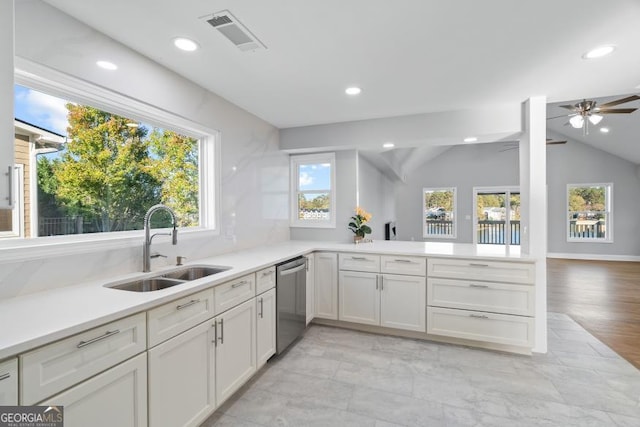 kitchen with visible vents, vaulted ceiling, light countertops, stainless steel dishwasher, and a sink