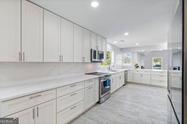 kitchen featuring stainless steel appliances, light countertops, white cabinetry, and recessed lighting