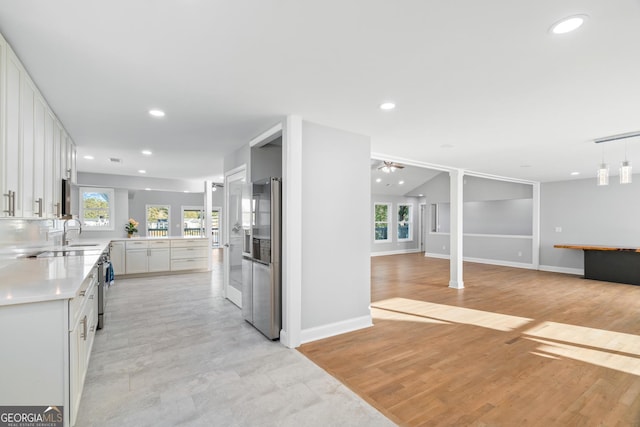 kitchen with recessed lighting, white cabinetry, open floor plan, light countertops, and stainless steel refrigerator with ice dispenser