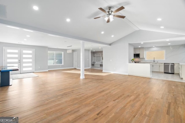 unfurnished living room featuring ceiling fan, a sink, baseboards, vaulted ceiling, and light wood-style floors