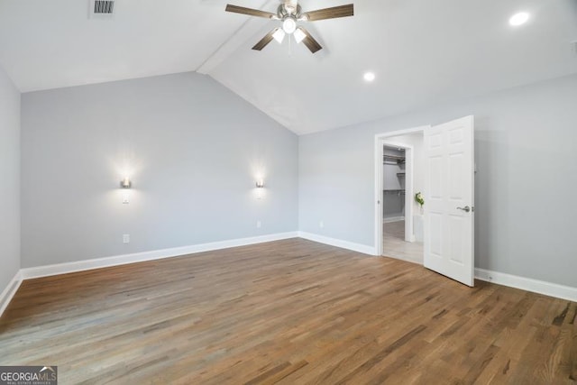 unfurnished bedroom with wood finished floors, visible vents, baseboards, vaulted ceiling, and a spacious closet