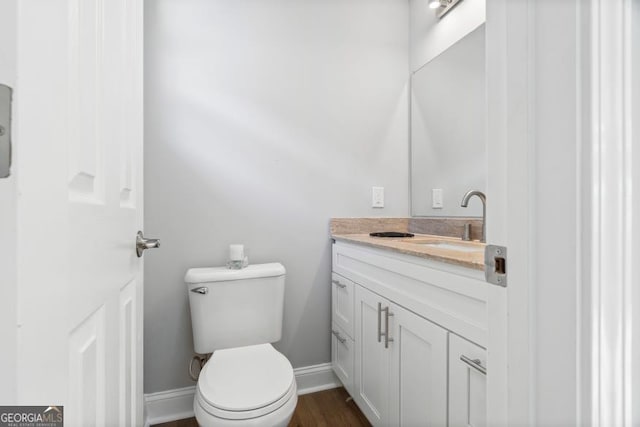 bathroom with baseboards, vanity, toilet, and wood finished floors