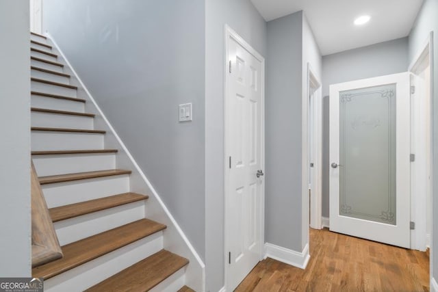 staircase featuring baseboards, wood finished floors, and recessed lighting