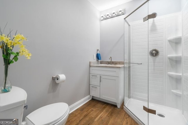 full bath with toilet, wood finished floors, vanity, baseboards, and a stall shower