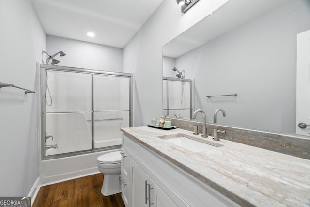 full bathroom with vanity, shower / bath combination with glass door, wood finished floors, and toilet