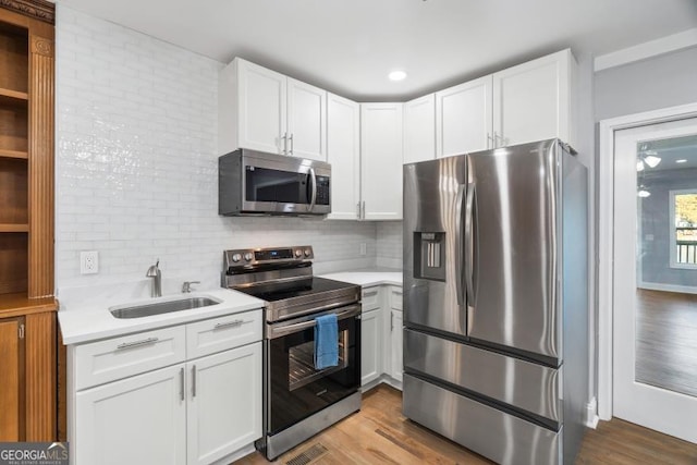 kitchen featuring white cabinets, appliances with stainless steel finishes, light countertops, and a sink