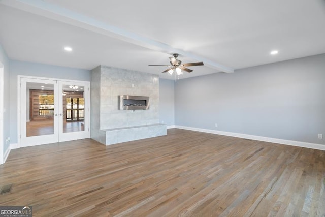 unfurnished living room with french doors, baseboards, beam ceiling, and wood finished floors