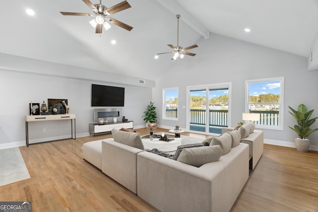 living room featuring high vaulted ceiling, light wood finished floors, beamed ceiling, and baseboards