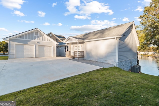 view of front of property featuring a garage, central AC unit, a water view, board and batten siding, and a front yard