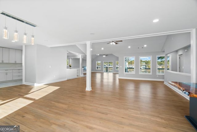 unfurnished living room with lofted ceiling, light wood-type flooring, a ceiling fan, and a healthy amount of sunlight