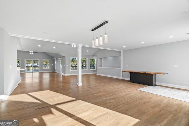 unfurnished living room with lofted ceiling, baseboards, recessed lighting, and wood finished floors