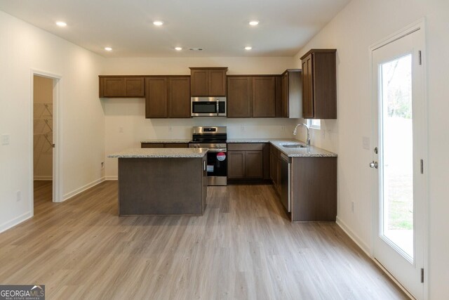 89 Hampton Ridge Way, Jefferson, GA 30549 - kitchen featuring stainless steel appliances, a sink, a center island, light wood-style flooring, and light stone counters