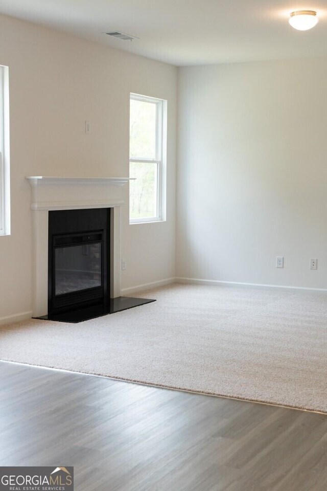 89 Hampton Ridge Way, Jefferson, GA 30549 - unfurnished living room featuring a glass covered fireplace, plenty of natural light, wood finished floors, and baseboards