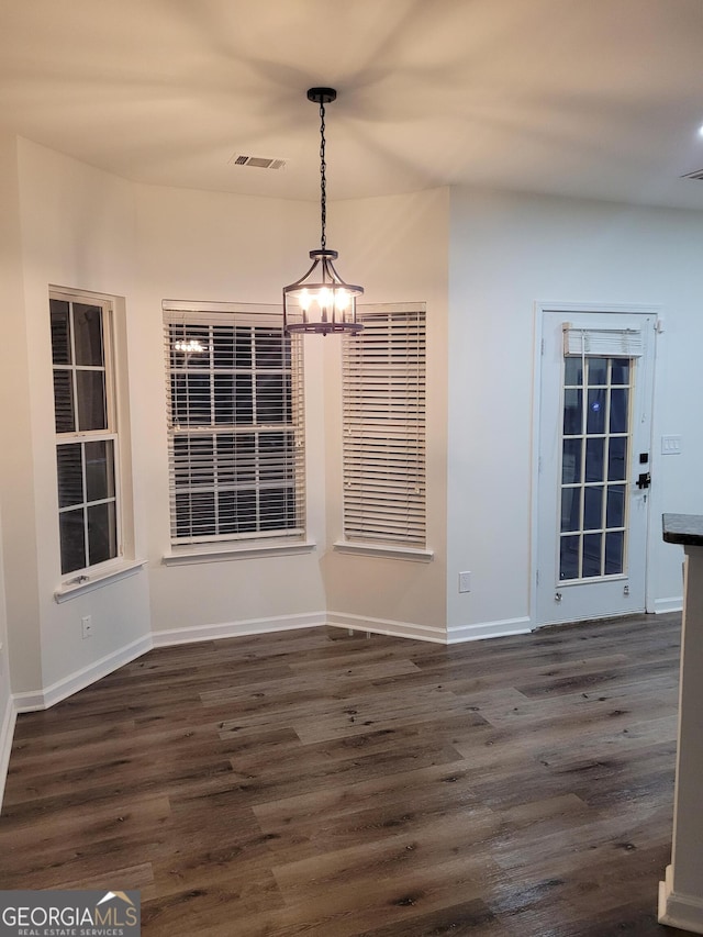 unfurnished dining area with dark hardwood / wood-style flooring and a notable chandelier