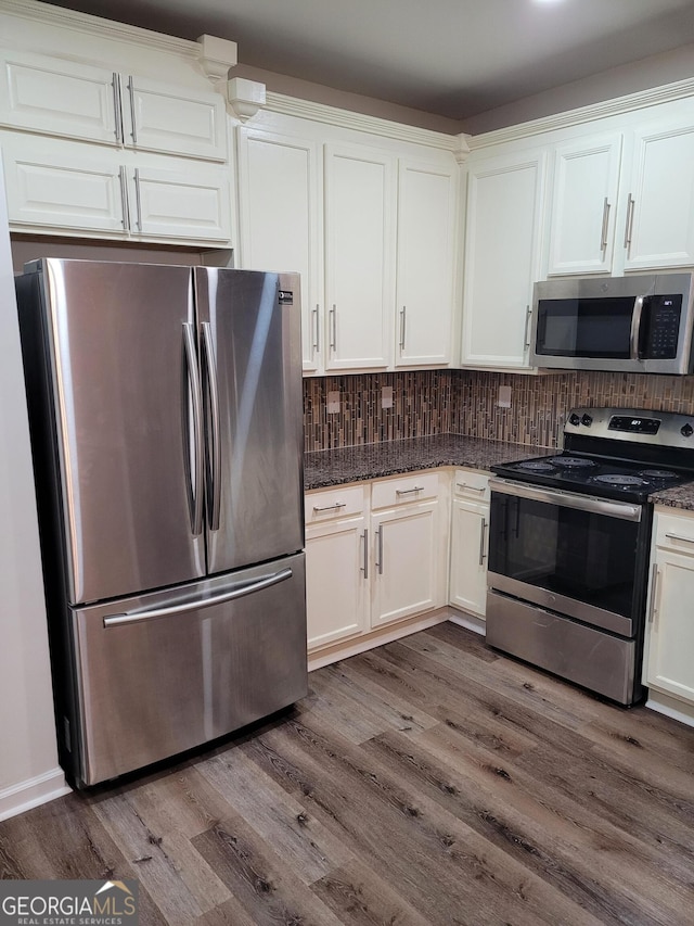 kitchen featuring white cabinets, dark hardwood / wood-style flooring, stainless steel appliances, and dark stone counters