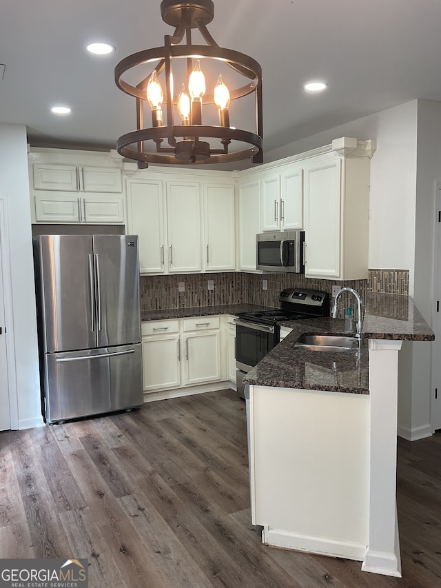 kitchen with appliances with stainless steel finishes, backsplash, sink, a chandelier, and hanging light fixtures