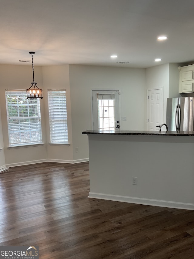 kitchen featuring a wealth of natural light, stainless steel fridge, dark stone countertops, and decorative light fixtures