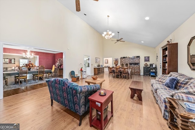 living room with light wood-type flooring, ceiling fan with notable chandelier, and high vaulted ceiling