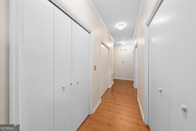 corridor with ornamental molding and light hardwood / wood-style floors