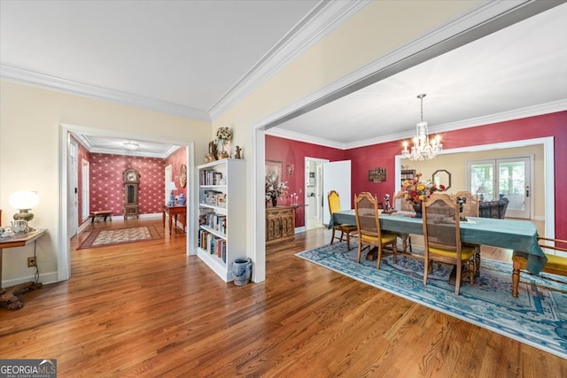 dining room featuring a wood stove, hardwood / wood-style floors, ornamental molding, and an inviting chandelier