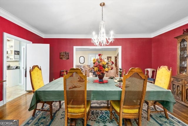 dining area featuring wood-type flooring, a chandelier, and ornamental molding