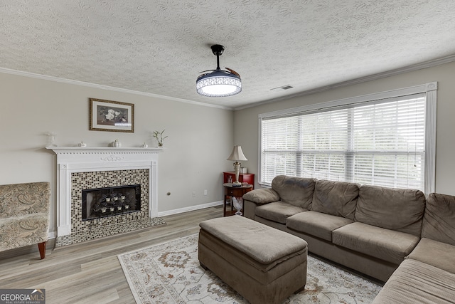 living room featuring a wealth of natural light, hardwood / wood-style flooring, ornamental molding, and a fireplace